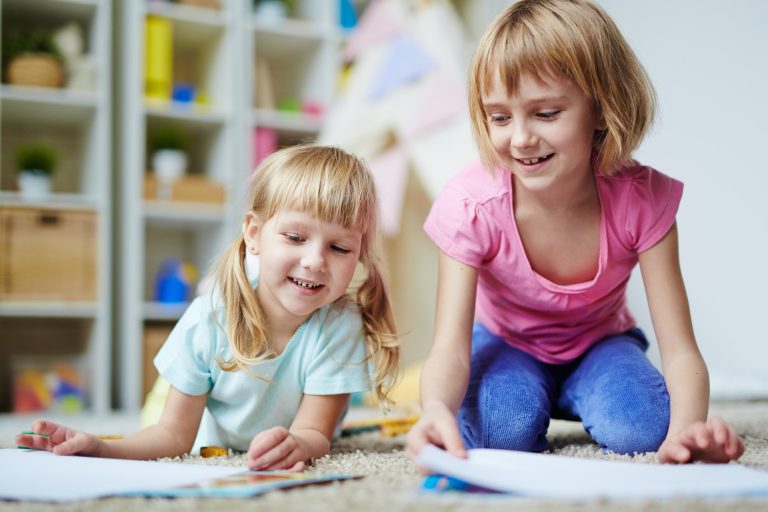 Two girls about 5 years old playing on the carpet.