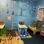 A colorful room filled with various toys and dolls scattered across the floor, creating a playful atmosphere.
