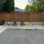 A backyard featuring a wooden fence and a designated play area with toys and equipment for children.