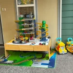 A colorful toy train table featuring a toy train and a toy car, designed for imaginative play.