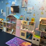 A colorful room filled with various toys and dolls scattered across the floor, creating a playful atmosphere.