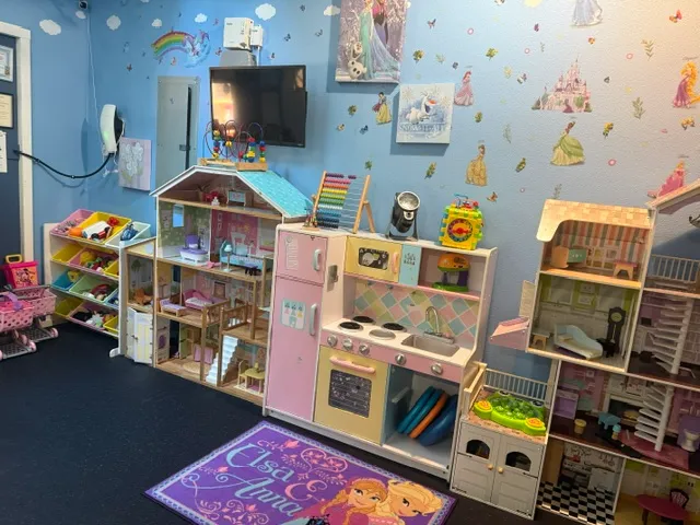 A colorful room filled with various toys and dolls scattered across the floor, creating a playful atmosphere.