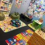 A playful child's room showcasing various toys and a decorative wall painted with a tree design.