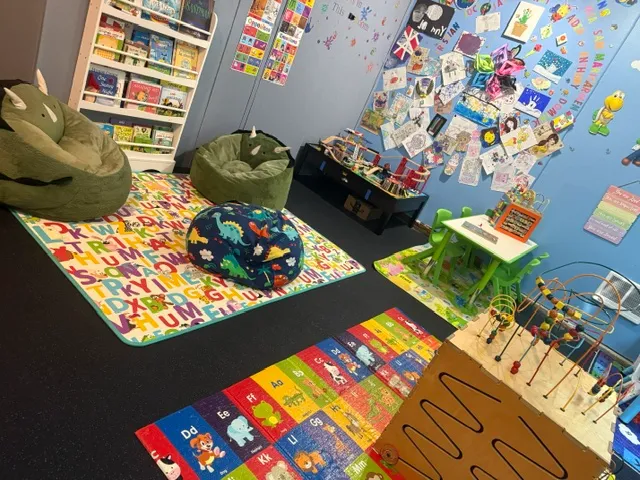 A playful child's room showcasing various toys and a decorative wall painted with a tree design.