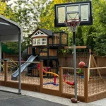 A backyard featuring a basketball court, swings, and a swing set, providing a space for outdoor recreation and play.